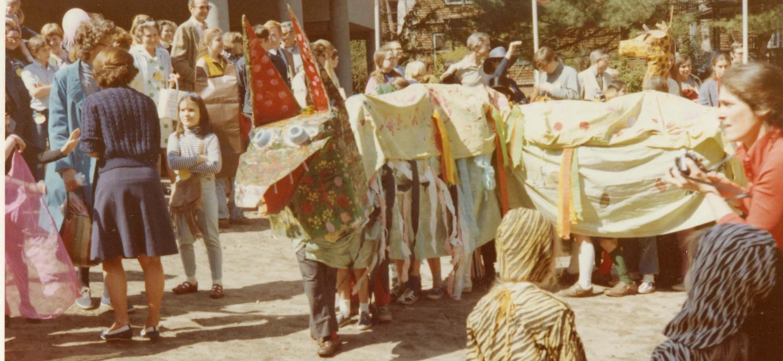 Vintage photo of large gathering with people in a long dragon creature costume.