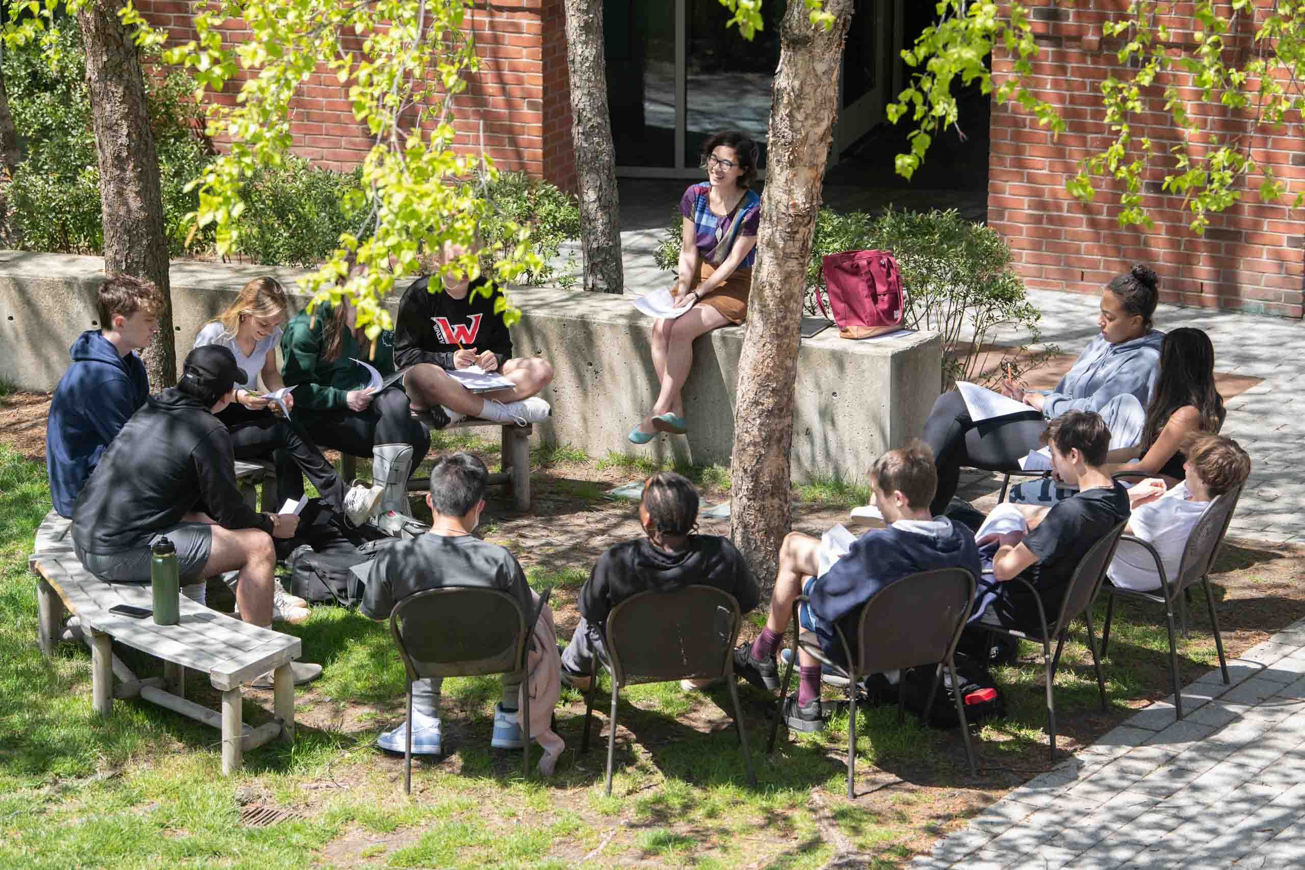 Students sitting in a semi-circle outside for class.