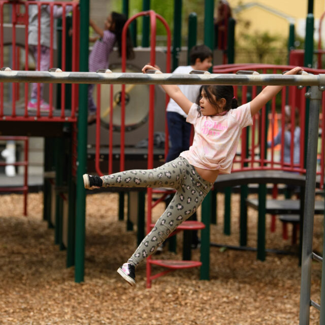 girl climbing on monkey bars.