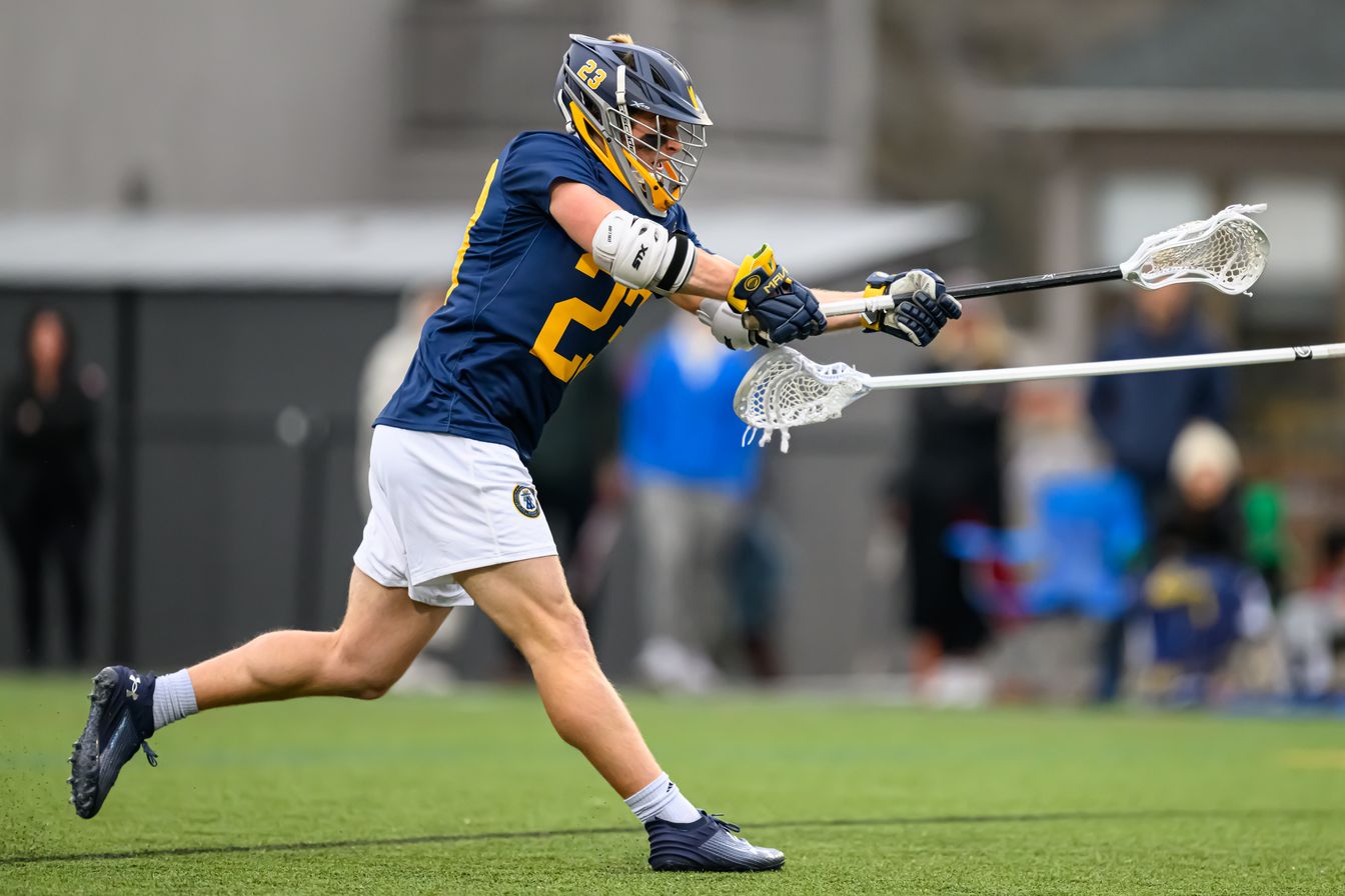 boy playing lacrosse in game.