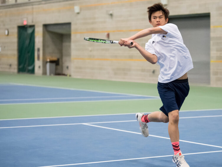 Boy returning tennis volley.