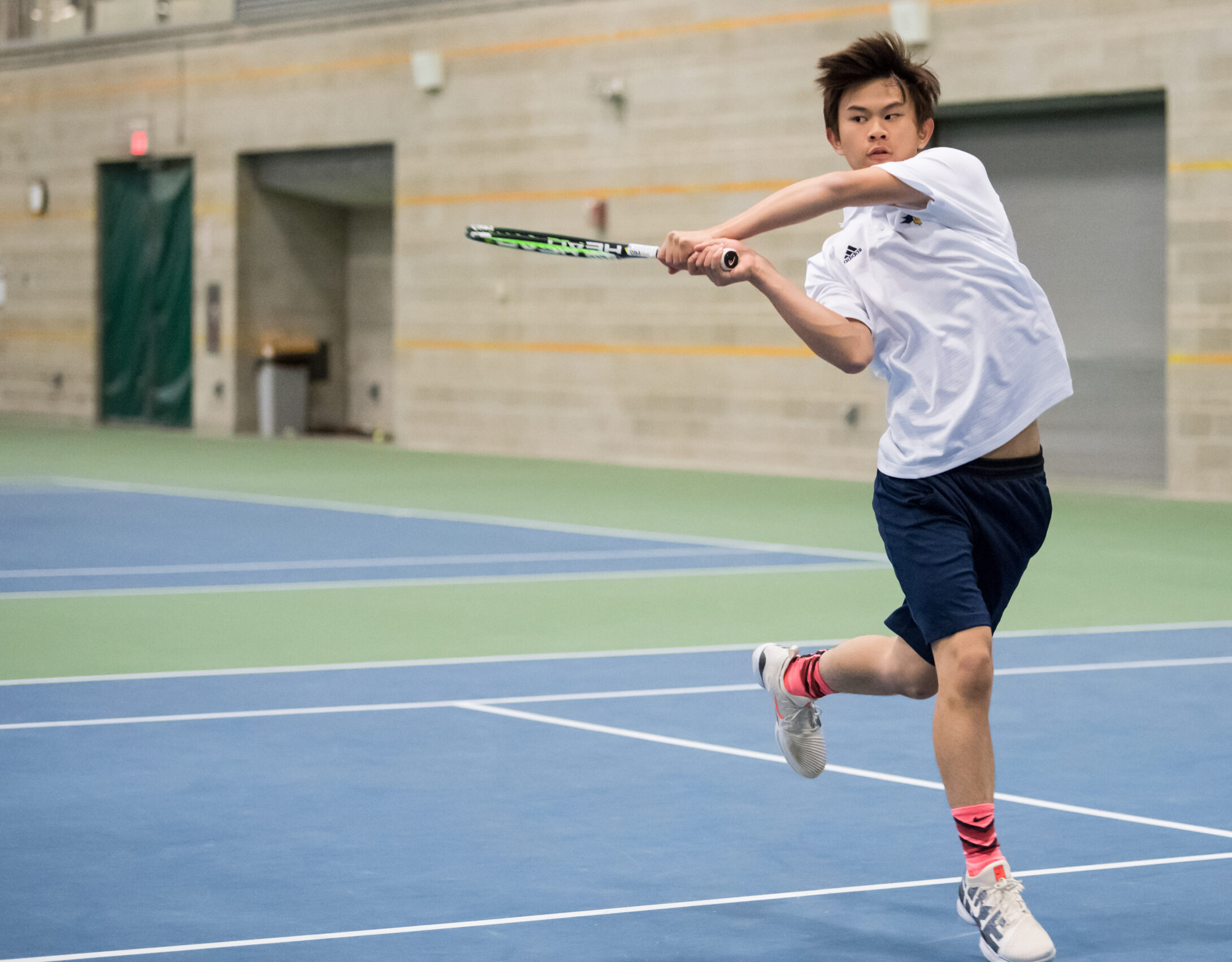 Boy returning tennis volley.