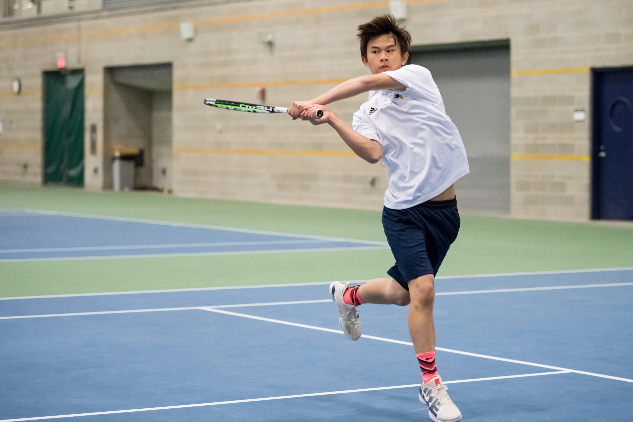 Boy returning tennis volley.