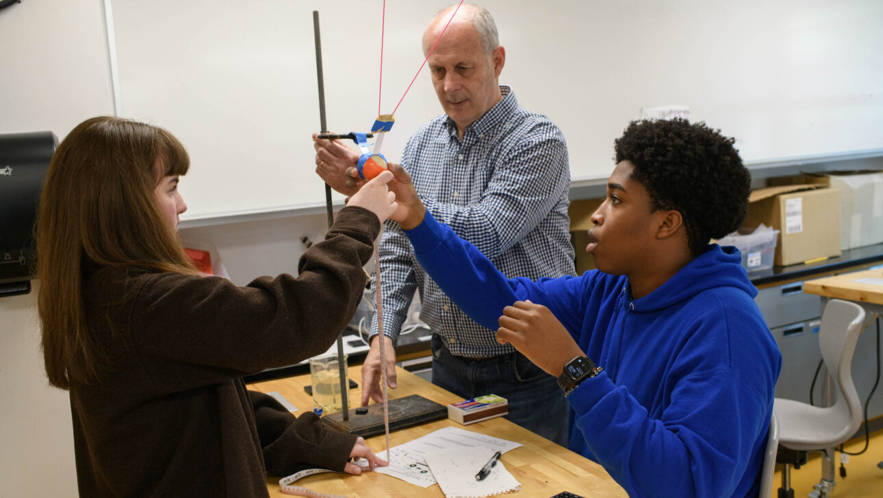 students working on physics experiment with teacher.