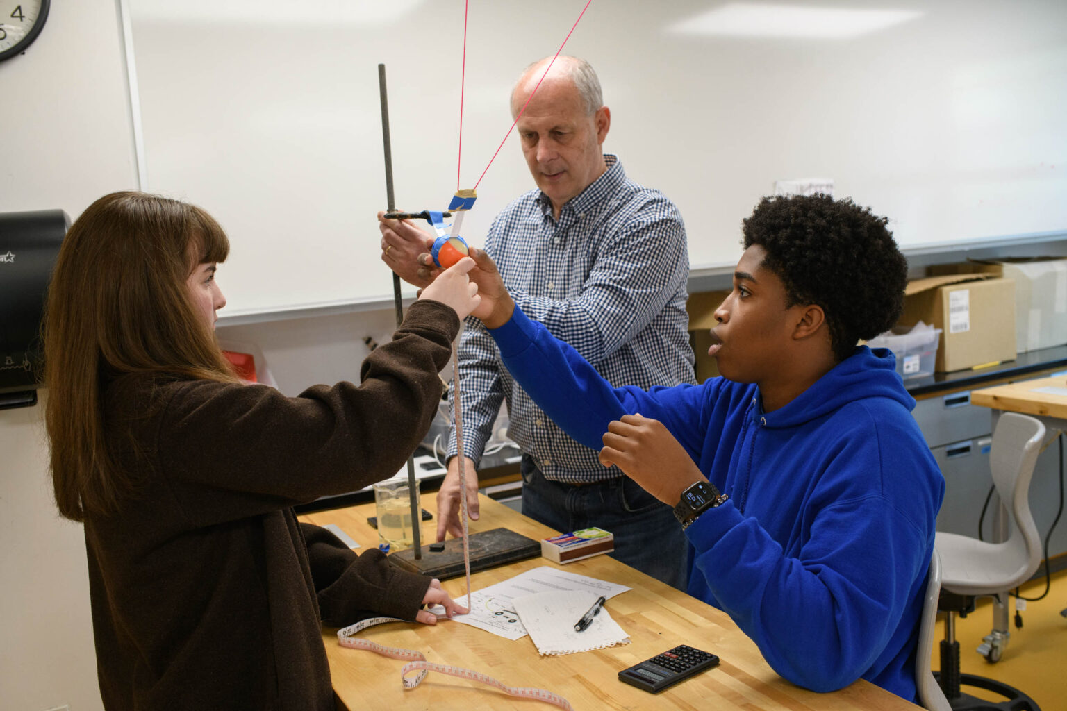 students working on physics experiment with teacher.