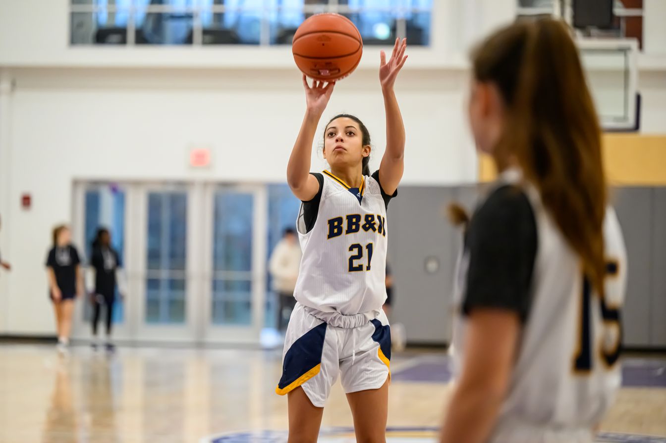 girl shooting basketball in game.