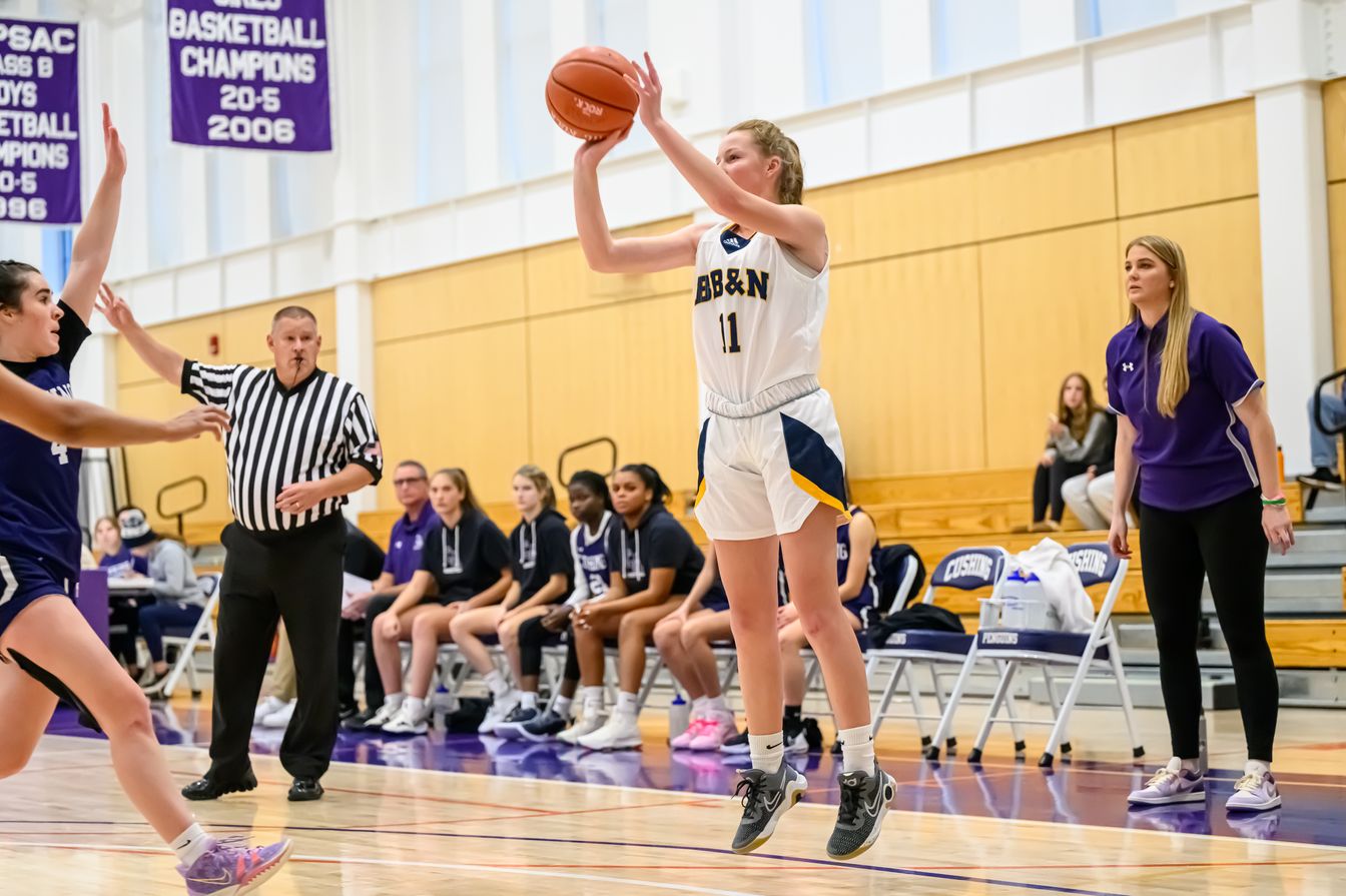 girl shooting basketball in game.