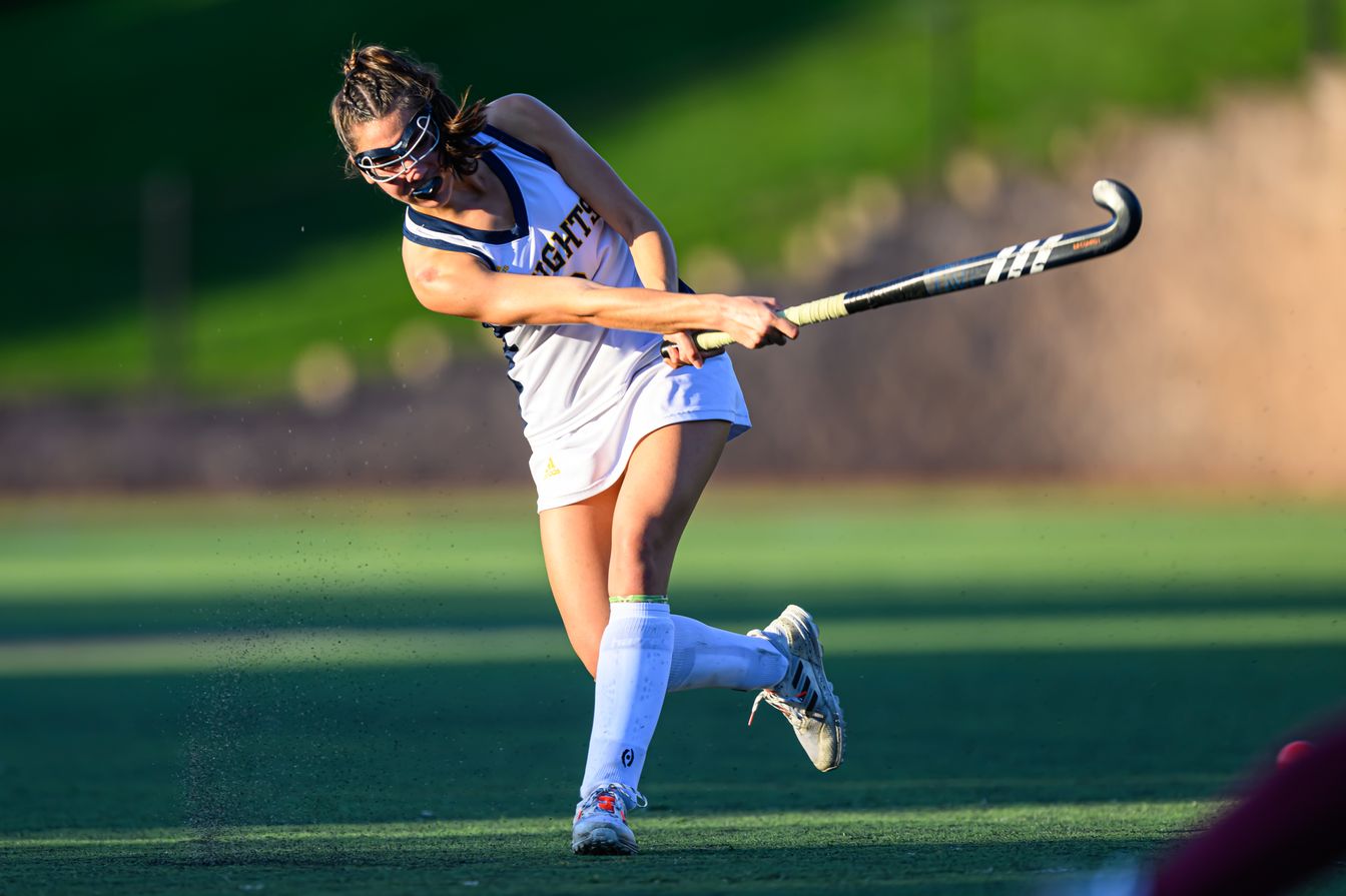 girl playing field hockey.