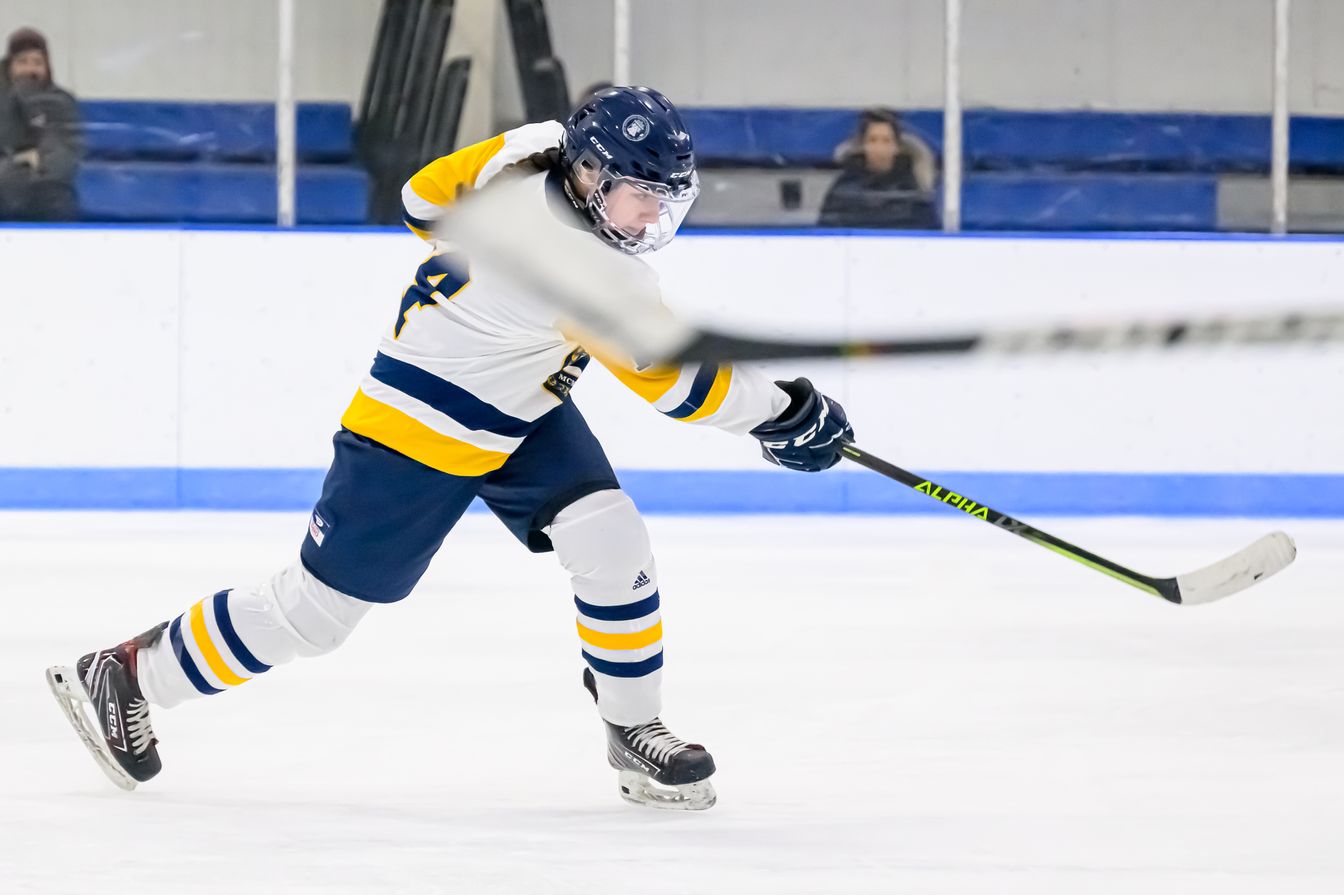 A female hockey player is in action on the ice.