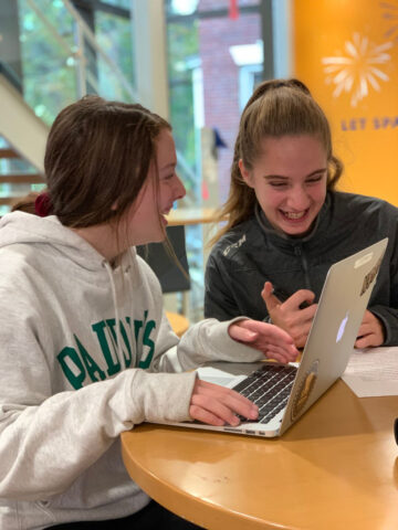 two students laughing and working together.