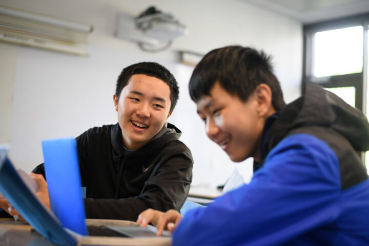 two students working together on laptops.