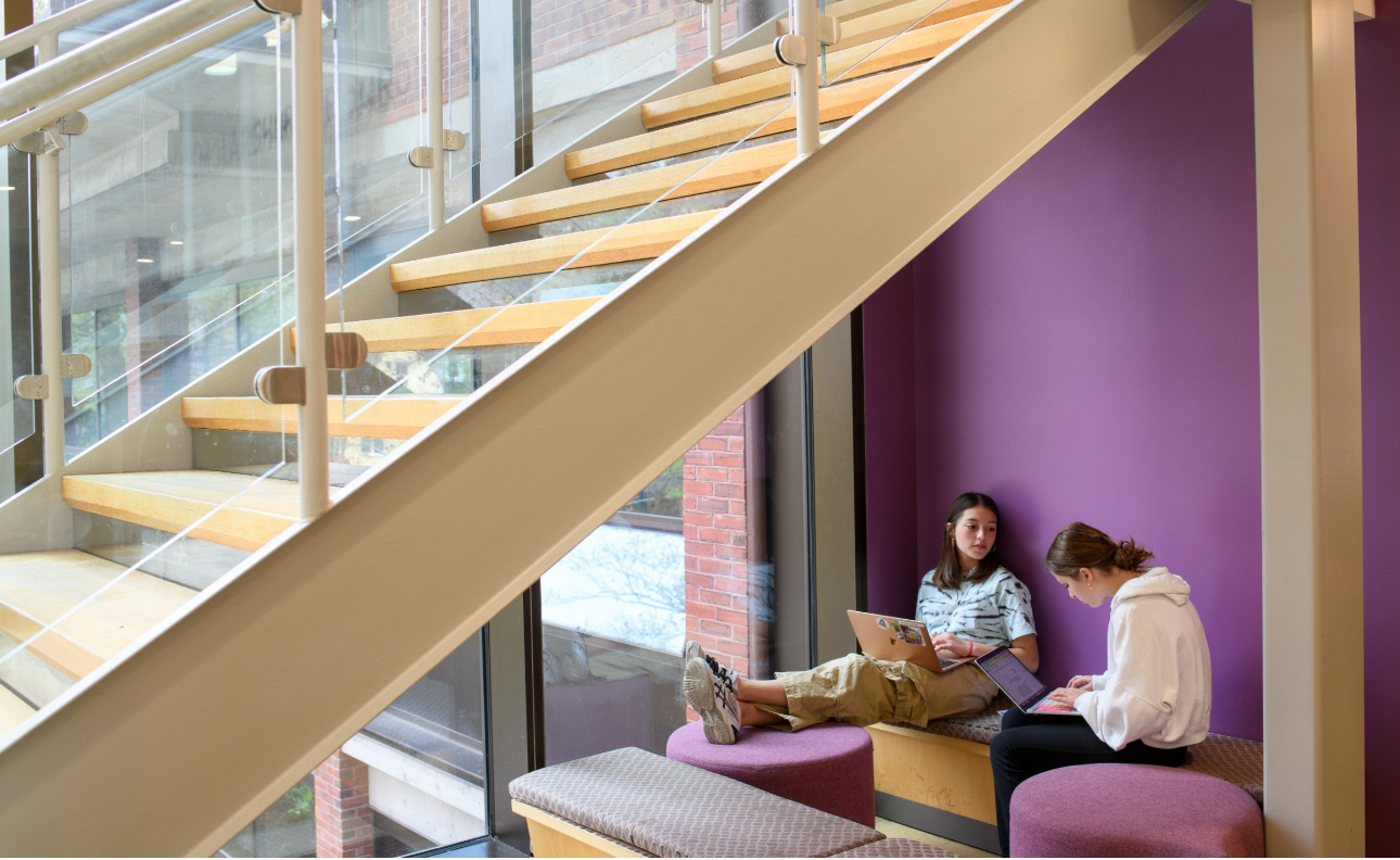 two students working under a staircase.