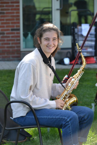 student with saxophone outside.