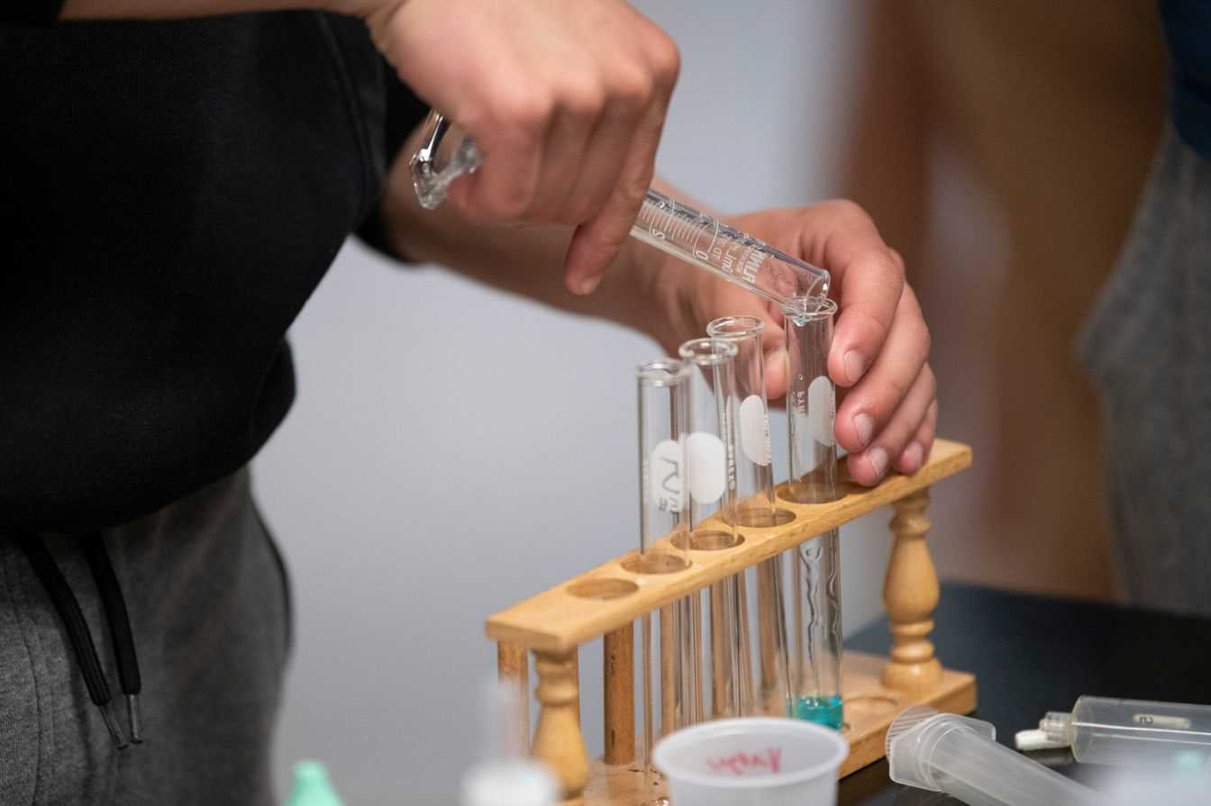 person pouring into test tubes.