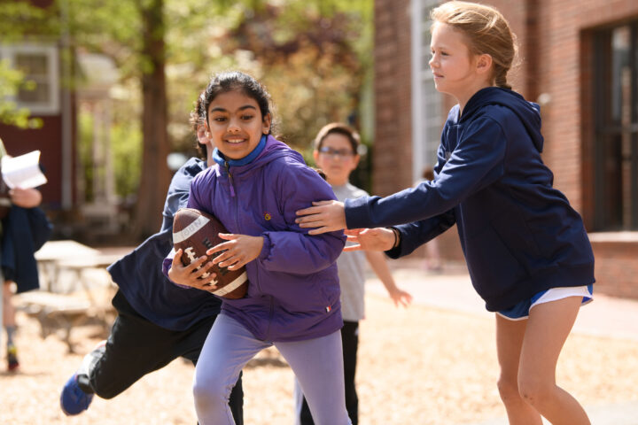 girls playing football outside.