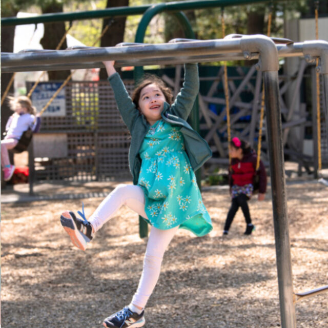 student hanging on monkeybars.