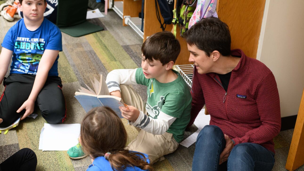 kids reading with teacher on floor.