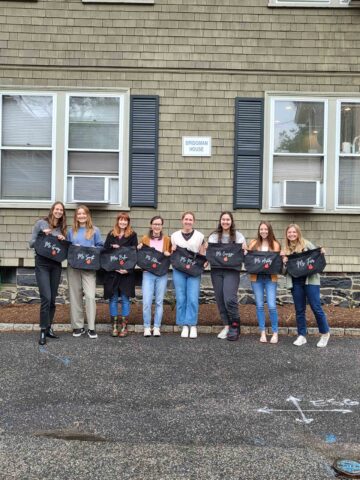 teachers in training holding tote bags outside.