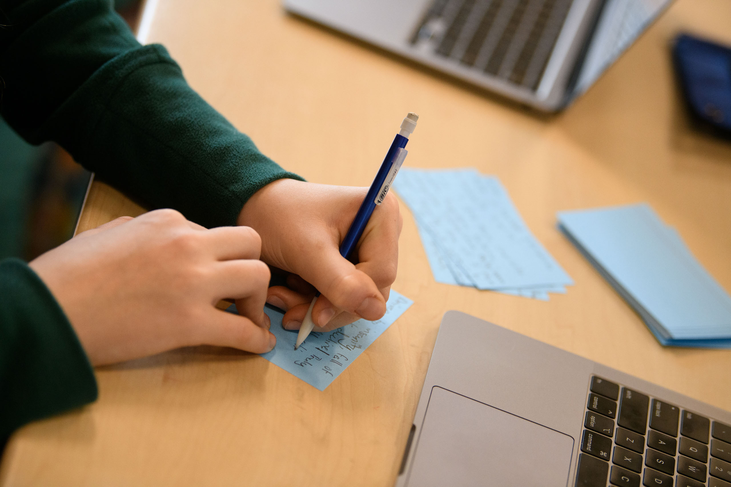 writing notes next to a laptop.