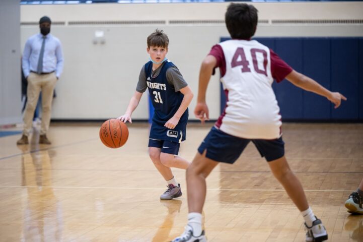 A young boy dribbling a basketball in a gym.
