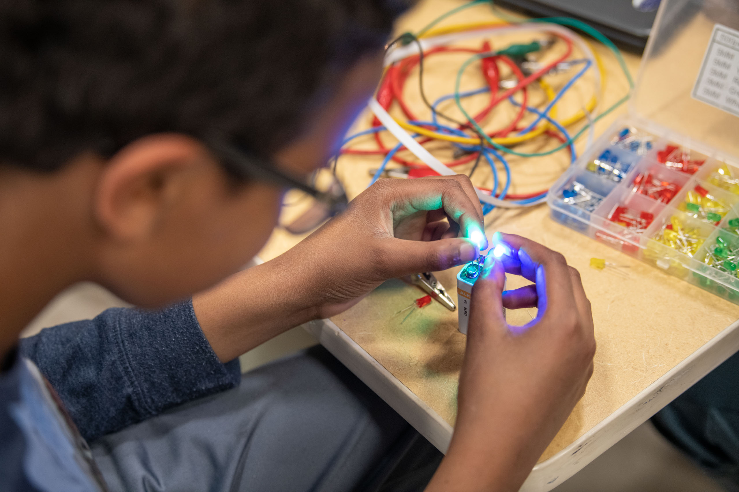 A boy is working on a circuit with colored wires.