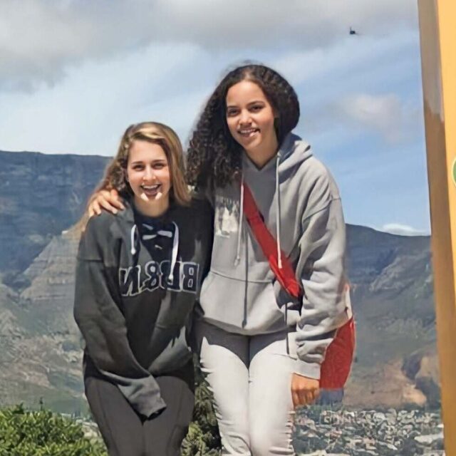 students posing in picture frame in front of landscape.