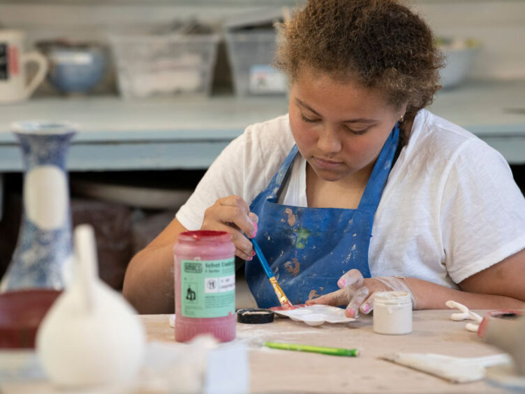 A young woman is working in a pottery studio.