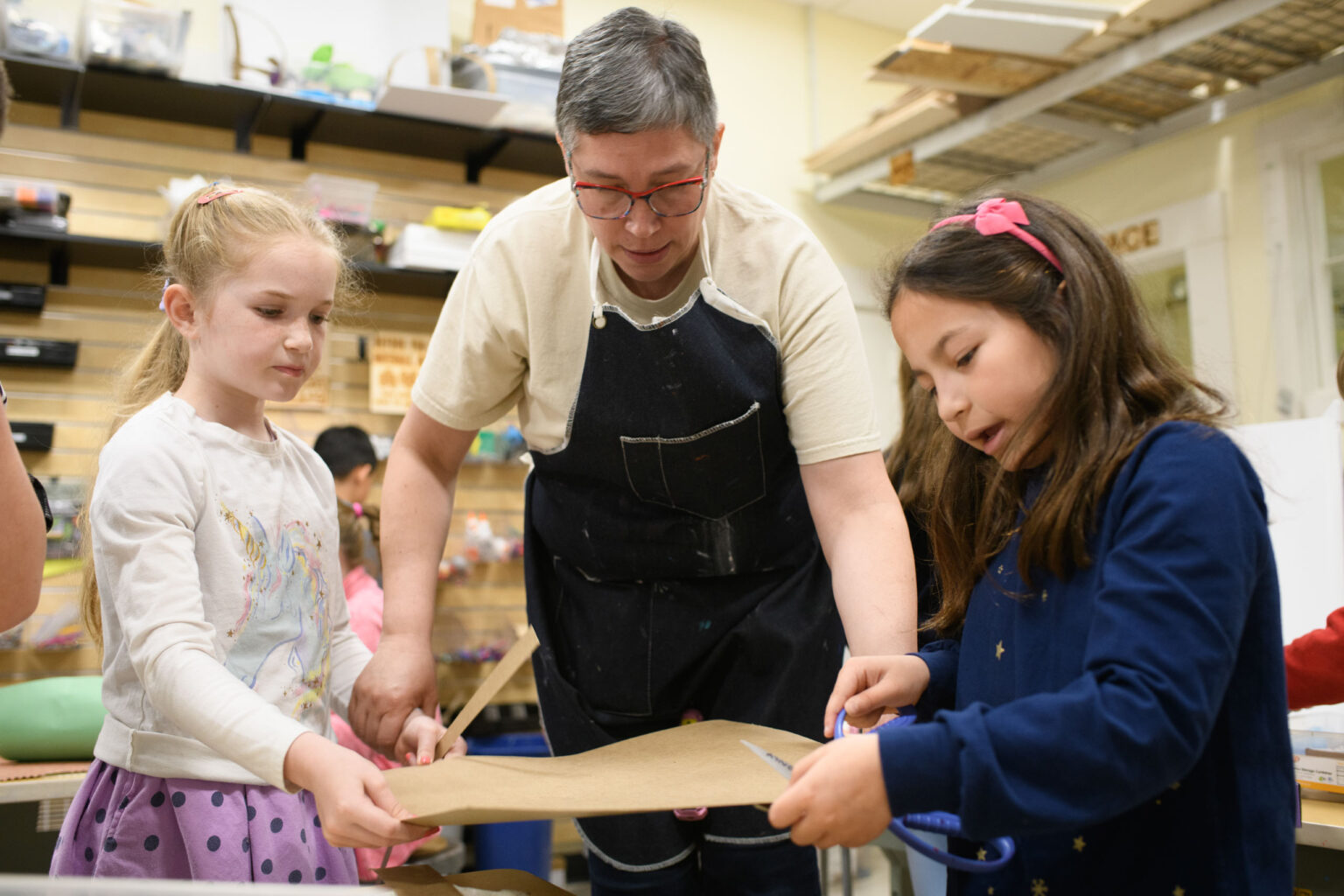 teacher demonstrating to two girls in class.