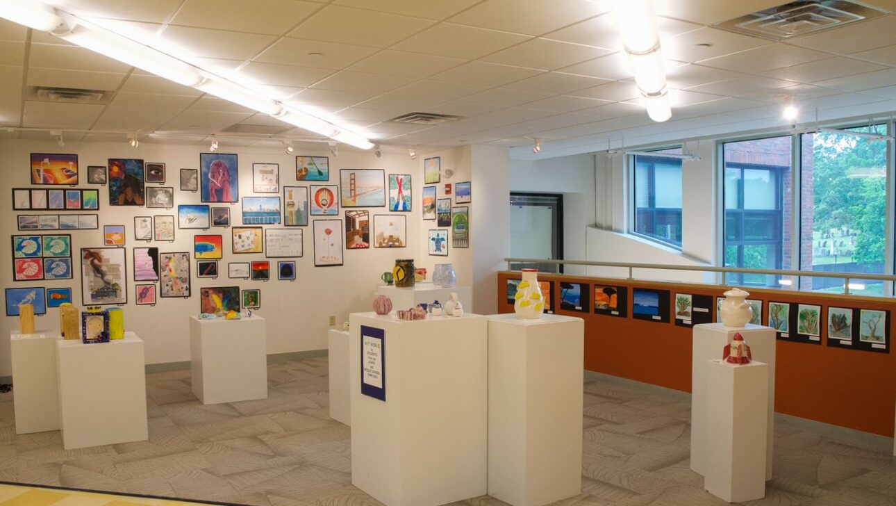 A brightly lit art gallery showcasing various paintings and sculptures.