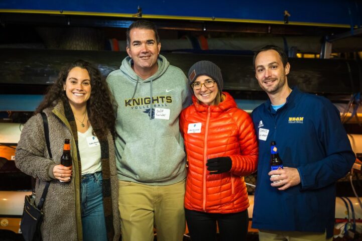 Four adults stand close together, smiling at the camera.