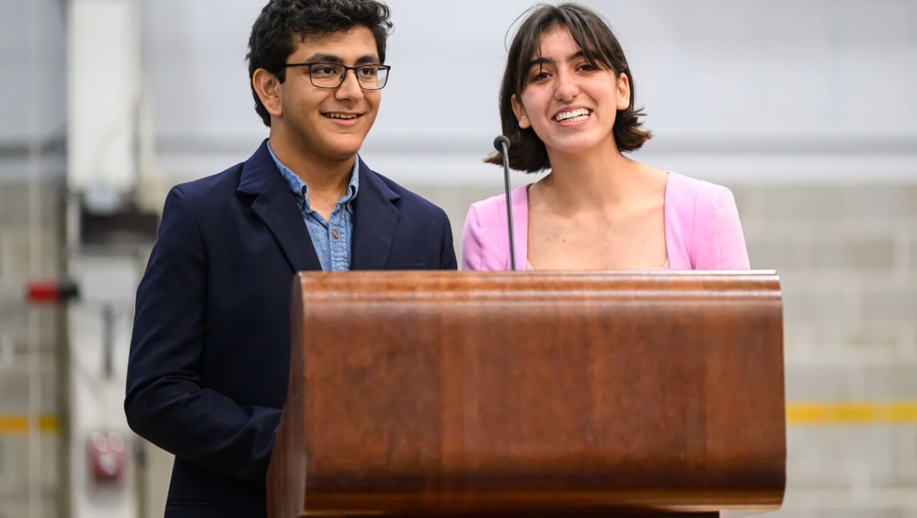 Two people standing behind a wooden podium, smiling.