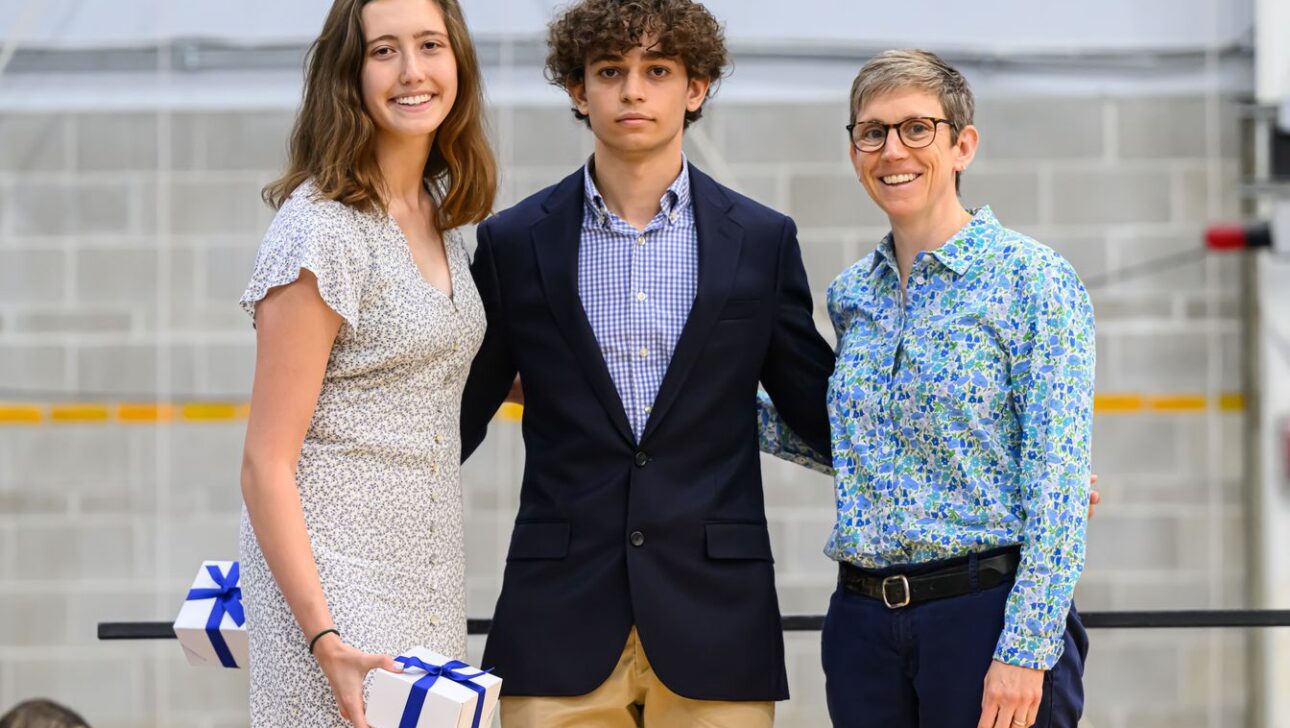 Three people posing for a photo; two on the left hold small gift boxes.