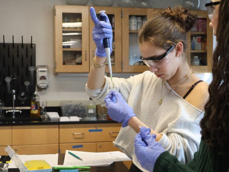 A female student pipettes a test tube during a science experiment